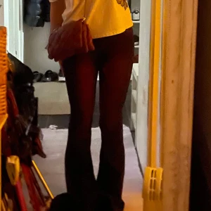 Mörklila/röd jeans monki bootcut - Säljer ett par mörklila jeansbyxor med klassisk bootcut passform och normal midja. Byxorna har fem fickor och stängs med dragkedja och knapp. Perfekta för dig som vill ha en stilren och enkel look.