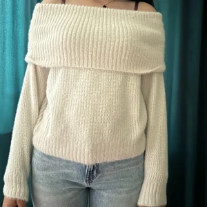 Offshoulder stickad vit tröja - Säljer en supermysig offshoulder stickad tröja i vit färg. Tröjan har bred ribbad kant upptill som ger en snygg och chill look. Perfekt till jeans och passar dig som gillar en lite loose passform och långa ärmar. Materialet är mjukt och värmande.