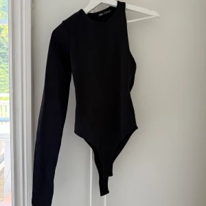 Assymetrisk oneshoulder body  - Säljer en svart body från Zara med linne på ena sidan och lång ärm på ena sidan. 