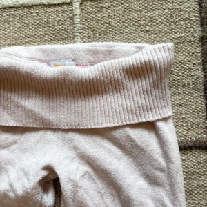 Ljusrosa mjukisbyxor från Gina Tricot - Supermysiga ljusrosa mjukisbyxor från Gina Tricot med bred ribbad midja och utsvängda ben. Byxorna är gjorda i ett mjukt och skönt material som passar perfekt för chill dagar hemma. Snygg och enkel design som är lätt att matcha.