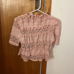 Rosa volangblus med spetsdetaljer - Supersöt rosa blus med volanger och spetsdetaljer. Bara andvänt 1 gång
