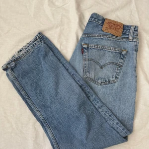 Levi's 501 ljusblå jeans W32 L32 - Klassiska Levi's 501 jeans i ljusblå tvätt med raka ben och lite högre midja. Jeansen har knappgylf, fem fickor och den ikoniska läderpatchen bak. Enda defekten är ett litet hål längst ned på vänstra benet, dock inget man märker enligt mig. Pris kan eventuellt diskuteras