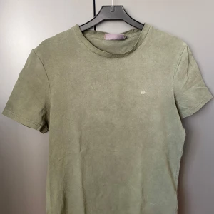 Olivgrön t-shirt från Morris XS - Olivgrön t-shirt från Morris Stockholm i mjuk bomull. Klassisk rund hals och korta ärmar. Diskret broderad logga på bröstet i vitt. Perfekt basic med clean look och snygg passform.
