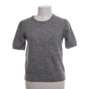 Grå stickad kortärmad tröja - Mörkgrå stickad tröja med korta ärmar och rund halsringning från hm. I storlek m men sitter mer som en xs/s! 