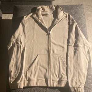 Beige hoodie med dragkedja från H&M - Säljer en beige hoodie från H&M i relaxed fit. Tröjan har hel dragkedja framtill, två fickor och hög krage. Materialet är mjukt och skönt, perfekt för chill dagar. Passformen är loose och ärmarna är långa. Enkel och stilren design som funkar till allt. Knappt använd alls. Säljer för det var fel storlek. 