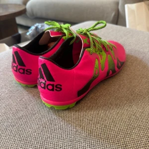 Adidas X 15.3 neonrosa fotbollsskor - Säljer ett par Adidas X 15.3 fotbollsskor i neonrosa med gröna detaljer och snörning. Skorna har svart sula med gröna partier och är tillverkade i syntetmaterial. Perfekta för dig som vill sticka ut på planen med en riktigt fet färgkombo. Storlek 45 1/2. De är små i storleken, jag har vanligtvis 44. Använda några gånger.
