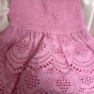 Rosa kort klänning med broderi - Supersöt rosa topp som även kan användas som en kjol. Kjolen har volanger och fina hålmönster som ger en romantisk vibe. Perfekt för dig som gillar pastell och detaljer. Klänningen är kort och gjord i mjukt bomullstyg. Köpte den förra året i Portugal och har inte använt den sen