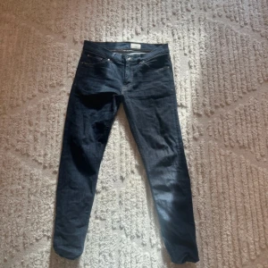 Mörkblå jeans från Tiger of Sweden - Snygga mörkblå jeans från Tiger of Sweden med klassisk femficksdesign och kontrastsömmar. Jeansen har rak passform och är tillverkade i ett mjukt bomullsmaterial med lite stretch. Perfekta för dig som gillar stilrena och tidlösa jeans.