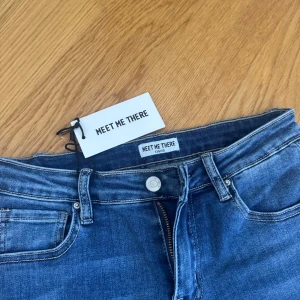 Blå jeans med stjärndetaljer Meet Me There - Snygga blå jeans från Meet Me There med raka ben och coola stjärndetaljer med pärlor på bakfickorna. Klassisk femficksmodell med dragkedja och knapp. Perfekta för dig som vill sticka ut lite extra.