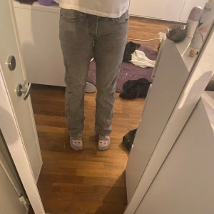 Grå raka jeans - Säljer ett par grå jeans med rak passform och klassisk femficksdesign. Jeansen har normal midja och är tillverkade i ett mjukt bomullsmaterial. Perfekta för dig som gillar en enkel och stilren look. Pris kan diskuteras.