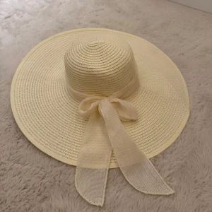 Beige solhatt med rosett - Hej! Säljer denna supersnygga beiga solhatten då den helt enkelt inte kommer till någon användning. Solhatten är stor och elegant med en söt rosett knyten på sidan. Perfekt att ha medans man solar om man vill se lite ”finare” ut. Den har aldrig blivit använd utan endast testad på och därav är den helt i nyskick utan några defekter. Om du skulle fundera över något är det bara att höra av dig, annars går det superbra att trycka på ”köp”. 
