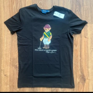 Svart Polo Bear t-shirt från Ralph Lauren - Svart Ralph Lauren T-shirt med nallebjörn tryck 🐎 👕  Storlek M✅  Helt ny 🆕   Pris går att diskutera 🤝 Går att köpa upp till 5 stycken! Hör av er vid frågor eller fler bilder :).