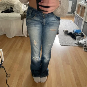 Blå bootcut jeans från Lee - Snygga Jeans från Lee med slitningar!🩷 Säljer för att dom är för långa för mig.                                       Midjemått: 37cm                                                             Ytterbenslängd: 110cm.                                                   Innerbenslängd: 88cm