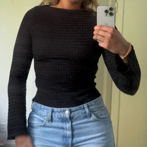 Svart strukturerad topp  - Svart långärmad topp från 157 i storlek S. Toppen har struktur med stretchigt material som sitter snyggt och markerar midjan. 