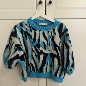 Zebra-mönstrad stickad tröja Zara - Cool stickad tröja från Zara med blå, svart och vit zebramönster. Tröjan har rund halsringning, ribbade muddar och en loose passform. Perfekt för dig som vill sticka ut med en unik look.
