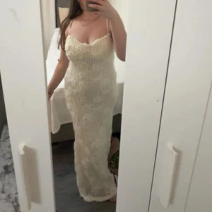 Lång vit spetsklänning med smala band - Säljer en elegant lång klänning i vit spets med smala axelband och v-ringad urringning. Klänningen har en figurnära passform och vackra spetsdetaljer som ger en romantisk känsla. Perfekt för dig som vill ha en stilren och feminin look.