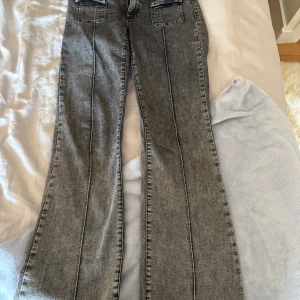 Grå bootcut jeans från NLY Jeans - Snygga grå jeans från NLY Jeans med bootcut-modell och markerade sömmar längs benen. Jeansen har två stora bakfickor och är tillverkade i klassiskt denimtyg. Perfekta för dig som gillar en retro vibe och vill sticka ut lite extra.