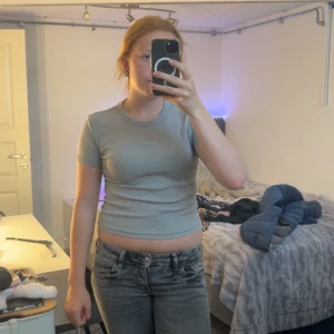 Grå ribbad croppad topp från Zara - Säljer en enkel och stilren grå croppad topp från Zara. T-shirten är ribbad, har rund halsringning och korta ärmar. Perfekt till jeans eller kjol för en chill look. Supermjuk och skön att bära.