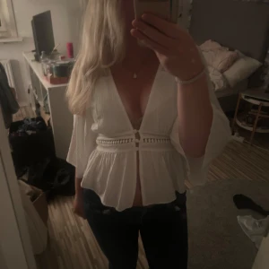 Vit blus med vida ärmar och knyt - Superfin vit blus med djup v-ringning, knappar framtill och snygga detaljer i midjan. Blusen har vida trekvartsärmar och ett luftigt tyg💗Använd ett fåtal gången och säljer på grund av brist på användning:)