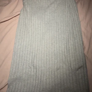 Grå ribbad långklänning Vero Moda - Långklänning från Vero Moda i ljusgrått ribbat tyg. Klänningen har en enkel och stilren design med diskret slits framtill. Perfekt för dig som gillar en clean och chill look. Materialet är mjukt och stretchigt för extra komfort.