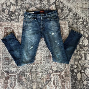Slim Glenn jeans - Snygga blå jeans från Jack and Jones, modell Slim Glenn med slim fit och slitna detaljer på benen