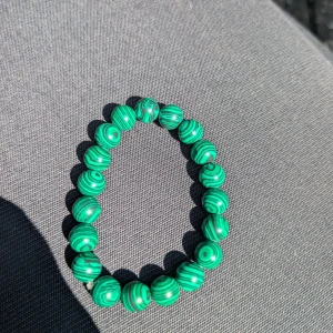 Grönt pärlarmband med randigt mönster - Snyggt armband med gröna pärlor i rund form och coolt randigt mönster. Pärlorna har en unik swirl-effekt som ger armbandet en riktigt fräsch vibe. Perfekt accessoar för att lyfta din stil med lite färg och personlighet. Passar vuxen 