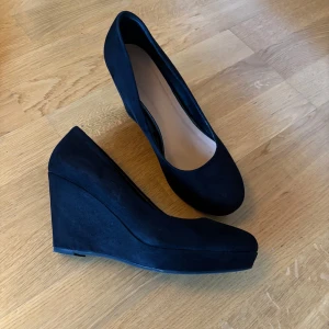 Svarta platåklackar  - Svarta platåklackar från märket Atmosphere, använda ett fåtal gånger och i bra skick förutom klacken på högra skon som har skrapats upp (se bild) 