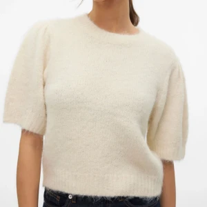 Vit stickad kortärmad tröja - Supermjuk och fluffig vit stickad tröja med korta ärmar och rund hals. Tröjan har en lätt oversized känsla och ribbade kanter vid ärmslut och nederkant. Perfekt att styla med jeans eller kjol för en chill look. Den är helt oanvänd och ganska ny. Köpte den i en större storlek för att den skulle bli lite oversized, så be om egna bilder om det behövs!💕