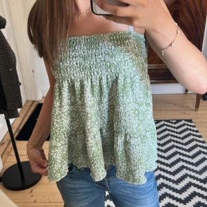 Grön blommig kjol/topp från Gina Tricot - Supersöt grön volang kjol från Gina Tricot med vitt blommönster. Går att använda som både kjol och topp! Den har inga defekter och jag skulle säga att den är som ny! Säljer för 180kr men pris kan diskuteras!