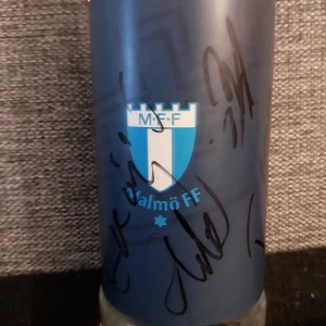 Signerad Röd ÖIF fotbollströja och en signerad MFF vattenflaska av taha Ali. Läs beskrivning  - Säljer en röd fotbollströja från Stadium med ÖIF-klubbmärke på bröstet och vita detaljer på axlarna. Tröjan är kortärmad och har en sportig passform i funktionsmaterial, perfekt för träning eller match. Signaturer finns på framsida av MFF spelare. Det finns också en MFF vattenflaska som är signerad av hela MFF klubben. Flaskan var överlämnad av taha Ali. En toppspelare i Malmö ff. Det går även att köpa dessa varor försig men helst ska de köpas tillsammans.   .(Pris kan diskuteras)