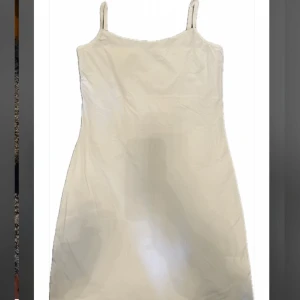 Vit kort klänning från Vila - Enkel och stilren helvit kort klänning från Vila. Klänningen har smala axelband och rak passform. Storlek M/L. 