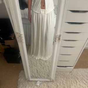 Vit långkjol från Gina Tricot XS - Superfin vit långkjol från Gina Tricot i flowigt material. Kjolen har resår i midjan för en bekväm passform och är perfekt för en chill och stilren look. Passar dig som gillar enkla och ljusa plagg med mycket rörelse.