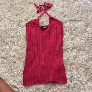 Rosa ribbad halterneck topp Bik Bok - Säljer en rosa ribbad halterneck topp från Bik Bok. Toppen är ärmlös med knytning i nacken och har en tight passform. Perfekt för varma dagar och enkel att styla med jeans eller kjol.