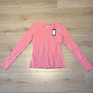 Rosa långärmad tröja från 157 - Säljer en enkel och snygg rosa långärmad tröja från 157. Tröjan är i mjuk bomull med lite stretch för en skön passform. Perfekt till jeans eller kjol och har en klassisk rund halsringning. Passar dig som gillar basic men ändå vill ha färg.