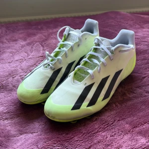 CRAZY FAST Fotbollskor - Snygga fotbollsskor från adidas i vitt och neongult med svarta ränder på sidorna. Skorna har snörning och är tillverkade i syntetmaterial med ventilerande mesh vid öppningen. Perfekta för dig som vill sticka ut på planen.