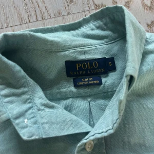 Mintgrön skjorta från Polo Ralph Lauren - Fräsch mintgrön skjorta från Polo Ralph Lauren i slim fit-modell. Klassisk button-down krage, långärmad och med broderad logga på bröstet. Skjortan är tillverkad i bomull och har knäppning framtill. Perfekt för dig som gillar stilrena och snygga plagg. Köpt för 1600kr, personen på bilden är 180!