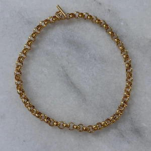Chunky guldhalsband med stora länkar - Snyggt chunky halsband i guld med stora, runda länkar och en stilren T-bar-låsning. Kedjan har en glansig finish som ger ett lyxigt intryck och passar perfekt för att lyfta vilken outfit som helst.