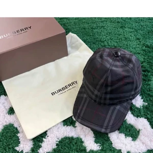  från Burberry - Snygg keps från Burberry i mörkgrått och svart med klassiskt rutigt mönster. Kepsen har böjd skärm och justerbar passform. Perfekt accessoar för att lyfta din streetstyle med en lyxig touch.