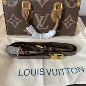 Louis Vuitton Monogram handväska - Säljer en ikonisk Louis Vuitton handväska i klassiskt monogrammönster. Väskan är brun och beige med guldiga metalldetaljer, två handtag och avtagbar axelrem. Insidan är fodrad i rött tyg och har dragkedja upptill. Perfekt för dig som vill sticka ut med lyxig design.