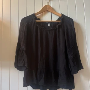 Svart blus med spets från Soyaconcept - Svart lite kortare blus från Soyaconcept med trekvartsärmar och volangdetaljer🥰Blusen har en lös passform och är tillverkad i ett lätt, krinklat bomullstyg. Ärmarna har inslag av spets som ger en extra touch. Perfekt för dig som gillar en chill och bohemisk vibe!🙏🏻💞 