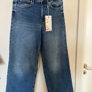 Blå wide jeans från ONLY, hög midja - Snygga blå jeans från ONLY i modellen Madison Blush HW Wide. De har hög midja och breda ben för en trendig och avslappnad look. Klassisk femficksdesign och tillverkade i mjukt denimtyg. Perfekta för dig som gillar en loose och bekväm passform.
