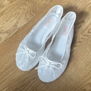 vita spets ballerinaskor från Nelly - ‼️Oanvända & rena‼️. Söta vita ballerinaskor från Nelly med spetsdetaljer och rosett framtill. 🩰🤍 Jag säljer dessa eftersom de är lite för stora på mig. Ordinarie pris: 350kr.