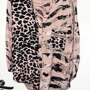 Leopardmönstrad skjorta M - Snygg skjorta med leopardmönster och abstrakta svarta och gråa ränder på en ljusrosa bas. Skjortan har knappar framtill, bröstficka och lång ärm. Bild 2-3: tråd har släppt.