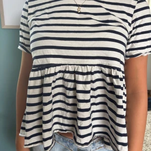 Randig kortklänning i bomull - Superfin tröja med marinblå och vita ränder. Den har en lös passform, korta ärmar och en söt volang nedtill. Perfekt för sommaren!🥰