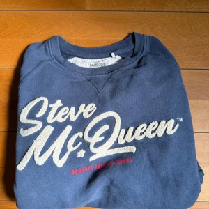 Barbour international - Steve McQueen tröja  - Snygg blå sweatshirt från Barbour International Steve McQueen-kollektionen. Tröjan har vit broderad text framtill och röd detalj, rund hals och långa ärmar. Använd, men i riktigt bra skick. Storlek M, men skulle säga att den sitter som S