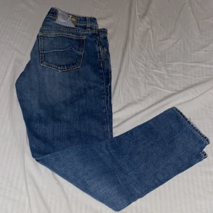 Blå jeans från Jacob Cohen  - Snygga blå jeans från Jacob Cohen med klassisk femficksdesign och raka ben. Jeansen har tydliga kontrastsömmar och en patch med logga bak i midjan. Tillverkade i mjukt denimtyg som ger en skön känsla och stilren look.
