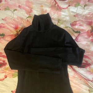 Svart polotröja med struktur från SHEIN - Svart polotröja från SHEIN i storlek L. Tröjan har ett snyggt strukturerat mönster i tyget och lång ärm. Perfekt för lager-på-lager och funkar till många olika outfits. Polokragen ger en clean och stilren look.