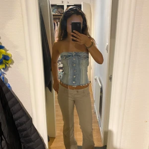 Beiga bootcut byxor med låg midja - Säljer ett par snygga beiga byxor med bootcut och låg midja. Byxorna har klassiska fickor fram och bak, bälteshällor och stängs med knapp och dragkedja. Perfekta för en clean och trendig look.