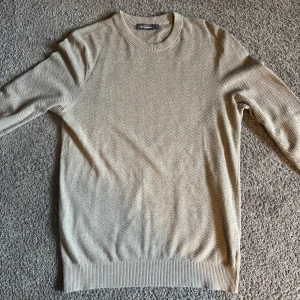 Beige stickad tröja från Dressmann - Snygg beige stickad tröja från Dressmann i storlek M. Tröjan är använd kanske tre gånger, men har inga tecken på användning, defekter eller slitage. 