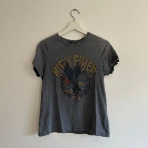 Grå t-shirt med vintage stil från Bik Bok - Grå t-shirt från Bik Bok med coolt vintageinspirerat tryck framtill. Klassisk rund halsringning och korta ärmar. Skön passform och mjukt bomullsmaterial. 